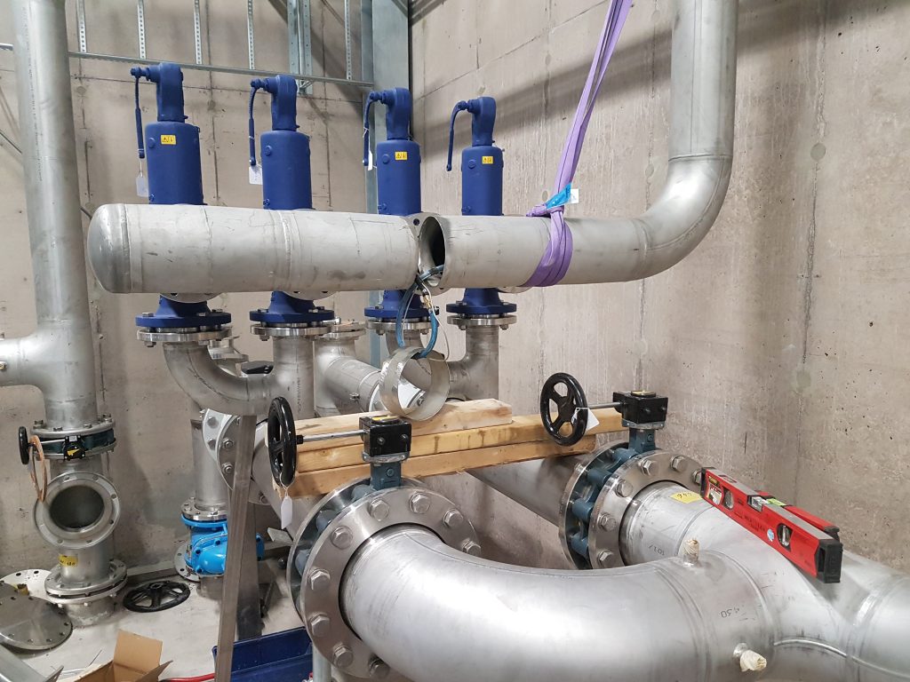 Four protective explosion-proof welders and a process piping manifold with an open joint ready for the final weld.