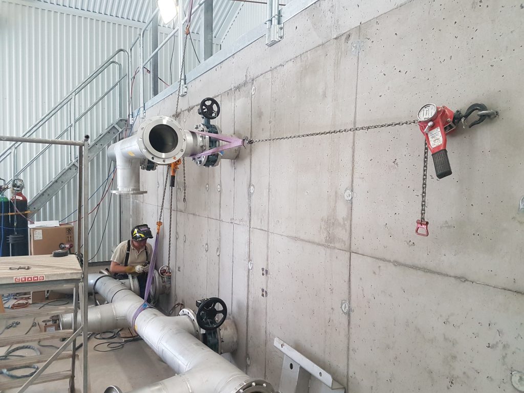 installer working on small fittings with process piping mounted on the wall