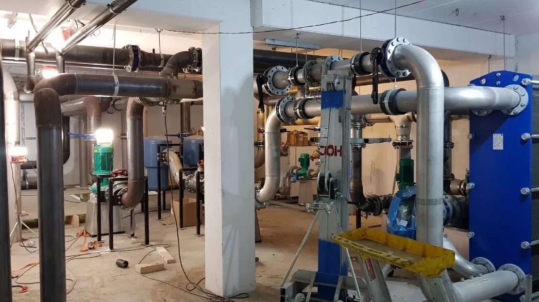 Färdigställt tekniskt rum inom rörmontage med installerade pumpar och kompressor – byggnadens klimatkontrollsystem.