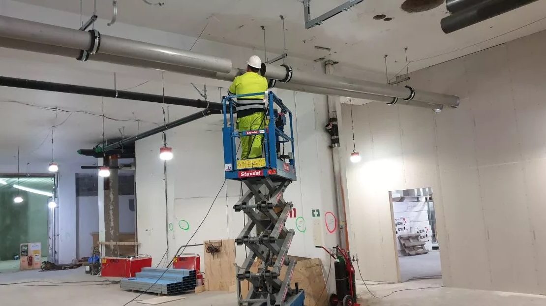 Arbetare på saxlift förbereder sig för rörmontage i Stockholm.