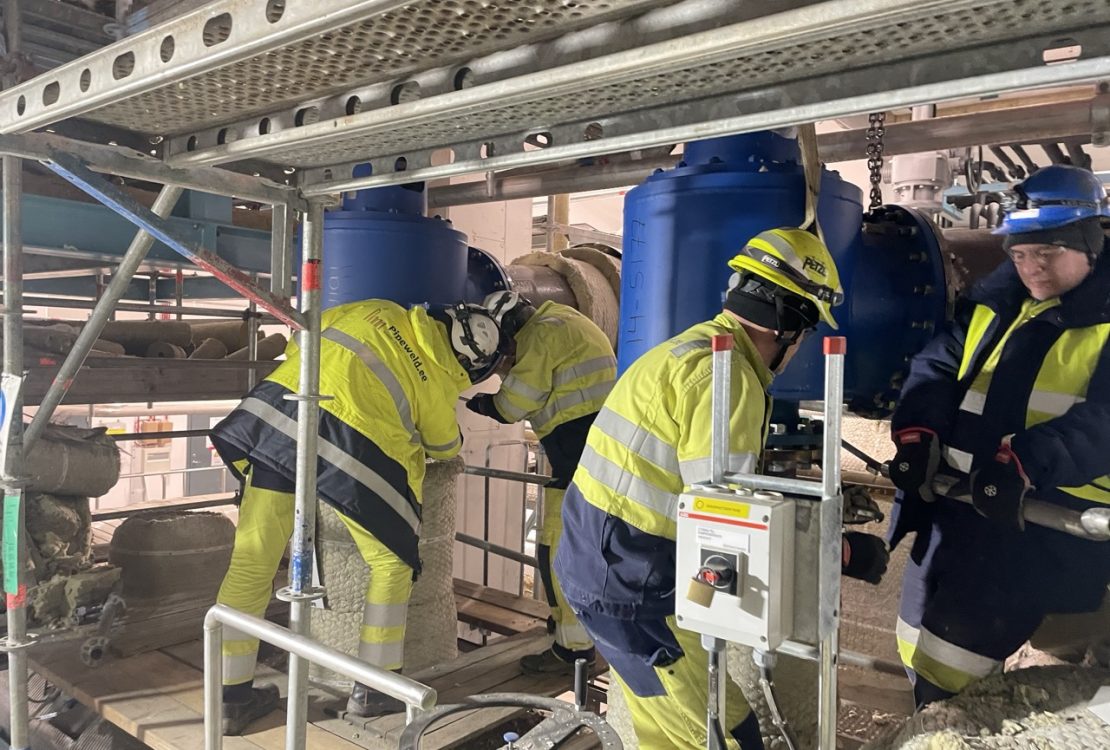 Industrial pipe fitters aligning pipe flange