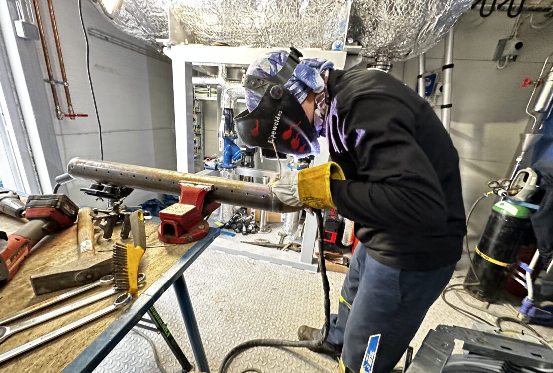 Mechanical Contractor — welder joining a pipe on a modular steam boiler, pipe from water feed tank.