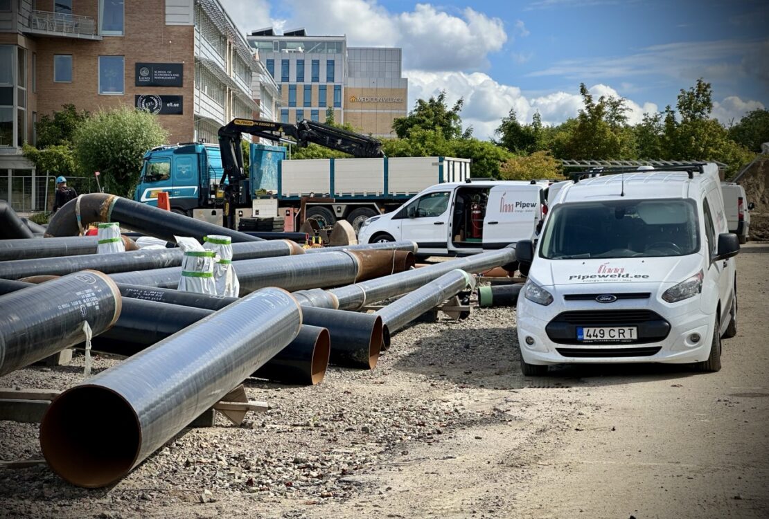 Pipes laid out outdoors, surrounded by vehicles with tools, as preparations for on-site pipe fabrication and prefabrication begin.