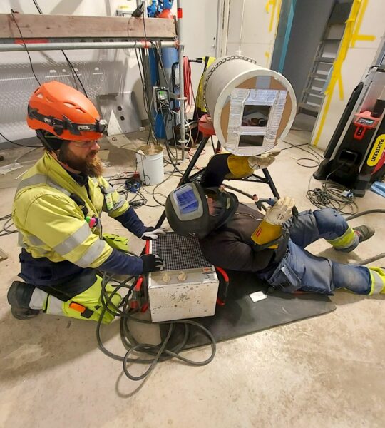 Welder and pipe fitter working together on industrial pipe spool fabrication, performed by a piping installation company